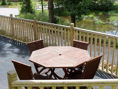 a wooden table and chairs on a deck with a fence at Rowanburn Lodge in Ellonby