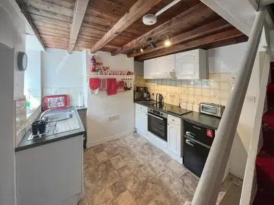 a small kitchen with white cabinets and black appliances at Ingle Neuk Cottage in Mosedale