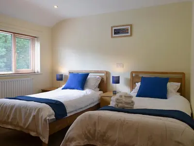 a bedroom with two beds with blue pillows and a window at Briar Rigg in Keswick