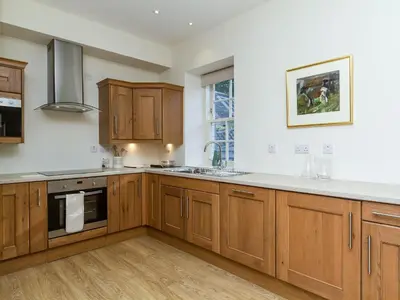 a kitchen with wooden cabinets and a counter top at Two The Stables in Dalrymple