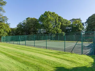 a tennis court with a fence around it at One The Stables in Dalrymple