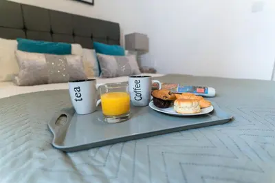 a tray of breakfast foods and orange juice on a bed at Irene Court Cockermouth in Cockermouth