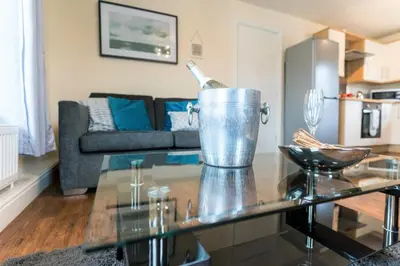 a living room with a glass table with a bottle on it at Irene Court Cockermouth in Cockermouth