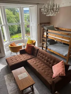 a living room with a brown couch and a table at Moffat Independent Hostel in Moffat