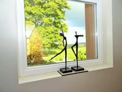 two sculptures sitting on a window sill in front of a window at Sharp Edge in Penrith