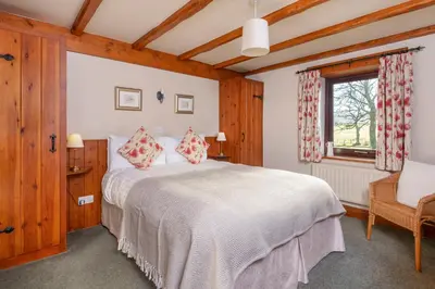 a bedroom with a bed and a chair and a window at Stable Barn in Penrith