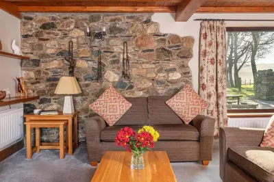 a living room with a couch and a stone wall at Stable Barn in Penrith