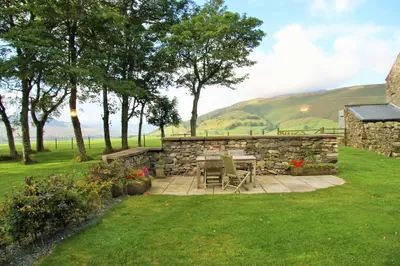 a patio with a table and a stone wall at Bannerdale in Penrith