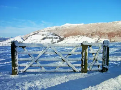 a gate in the snow with a mountain in the background at Grisdale View in Penrith