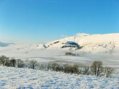 a snow covered hill with a mountain in the background at Grisdale View in Penrith