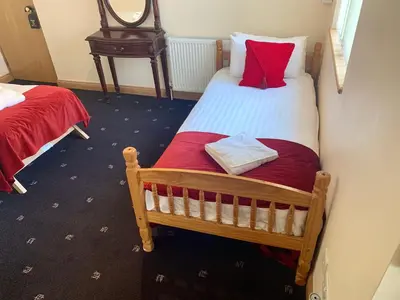 a bedroom with two twin beds with red pillows at Glenlossie Guest House in Dumfries