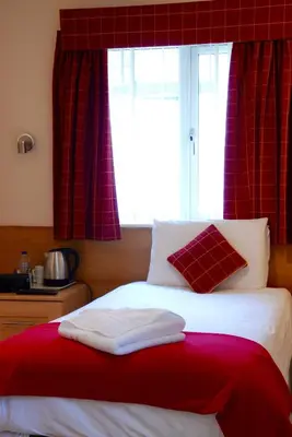 a bed with a red blanket and a window at Glenlossie Guest House in Dumfries