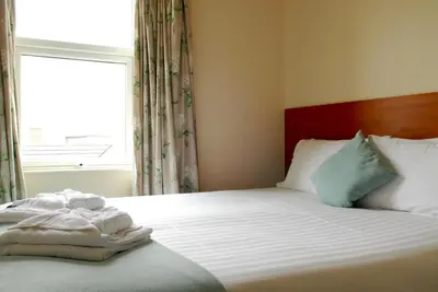 a bed in a room with a window and a bedvisor at Glenlossie Guest House in Dumfries