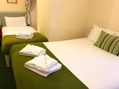 two beds in a room with towels on them at Glenlossie Guest House in Dumfries