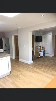 an empty living room with wooden floors and a kitchen at Ancrum House in Gretna Green