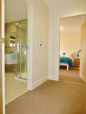 a bathroom with a glass shower and a bedroom at Cairndoon Byre in Monreith