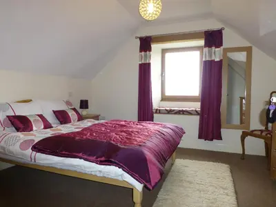 a bedroom with a bed with purple sheets and a window at Cairndoon Byre in Monreith
