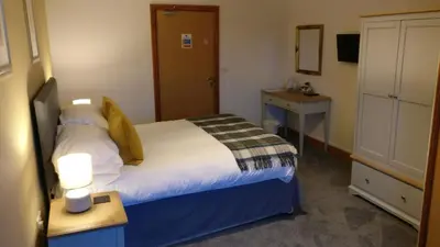 a bedroom with a bed and a table and a drawer at The Mansion in Whitehaven