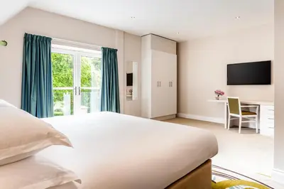 a bedroom with a large white bed and a desk at The Daffodil Hotel & Spa in Grasmere