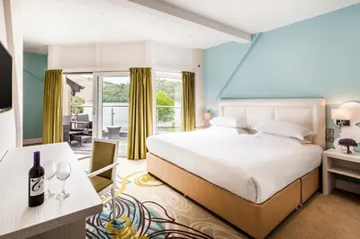 a bedroom with a king sized bed and a dining room at The Daffodil Hotel & Spa in Grasmere