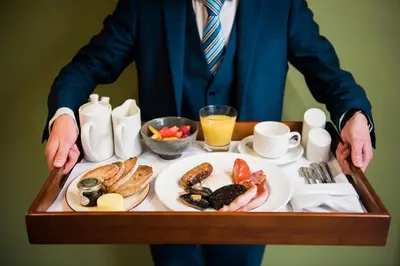 a man is holding a tray of breakfast food at The Daffodil Hotel & Spa in Grasmere
