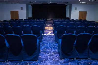 an empty room with blue chairs and a stage at The Park Hotel in Kilmarnock