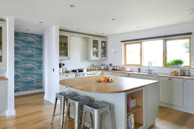 a kitchen with a large island with bar stools at Airds Bay Luxury Beach House in Gatehouse of Fleet