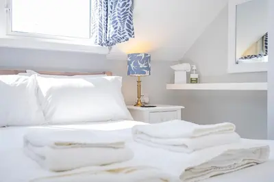 a white bed with white sheets and towels on it at Cragwood Guest House in Keswick