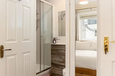 a bathroom with a glass shower and a bed at Cragwood Guest House in Keswick
