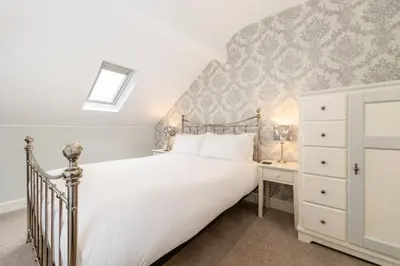 a bedroom with a large white bed and a dresser at Cragwood Guest House in Keswick