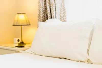 a bed with a white pillow and a lamp on a table at Cragwood Guest House in Keswick