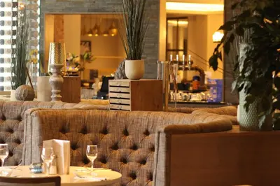 a couch in a restaurant with two tables and wine glasses at Riverside Lodge Hotel in Irvine