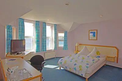 a bedroom with a bed and a desk and a tv at The Penta in Douglas
