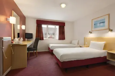a hotel room with two beds and a desk at Days Inn Hotel Gretna Green in Gretna Green