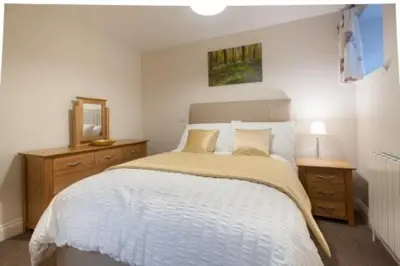 a bedroom with a bed and a dresser and a mirror at Milntown Self Catering Apartments in Ramsey