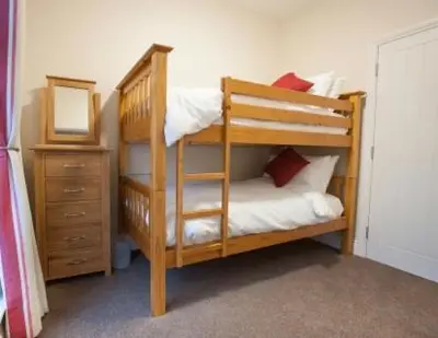 a wooden bunk bed with a mirror and a dresser at Milntown Self Catering Apartments in Ramsey