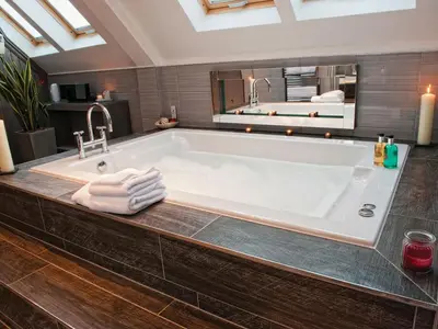 a bathroom with a large white tub with a mirror at The Gailes Hotel & Spa in Irvine