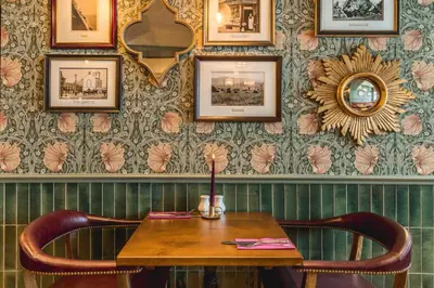 a table and chairs in a room with a wall at The Kings Arms Hotel in Keswick