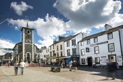 a group of people walking down a street with a clock tower at The Kings Arms Hotel in Keswick