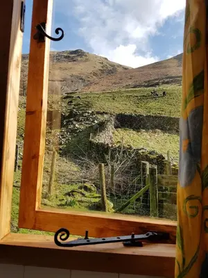 a window with a view of a field at Stybeck Farm Shephards Hut in Thirlmere