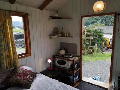 a bedroom with a bed and a tv and a window at Stybeck Farm Shephards Hut in Thirlmere