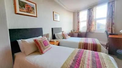 a hotel room with two beds and two windows at The Hydro Hotel in Douglas