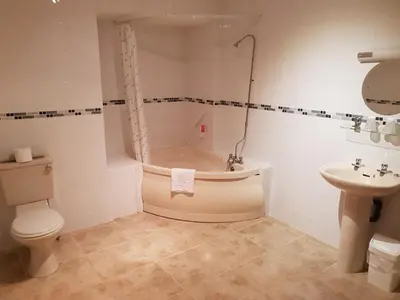 a bathroom with a tub and a toilet and a sink at Ascot Hotel in Douglas