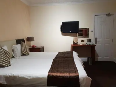a hotel room with a bed and a flat screen tv at Ascot Hotel in Douglas