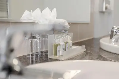 a bathroom counter with bottles of soap and a sink at Claremont Hotel in Douglas