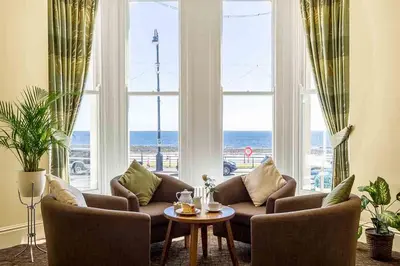 a living room with a couch and a table in front of a window at The Rutland Hotel in Douglas