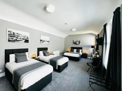 a hotel room with two beds and a chair at The Chesterhouse in Douglas