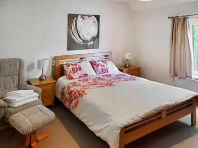 a bedroom with a large bed and a chair at Crossfeld in Keswick