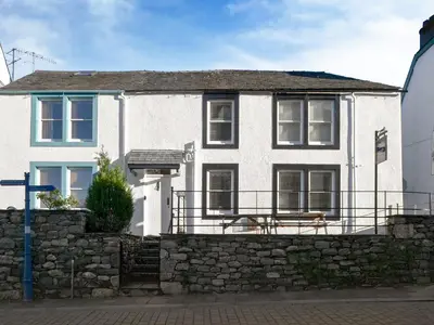 a white house with a stone wall at Rose Patch Cottage in Keswick