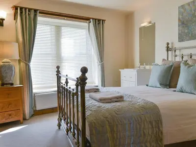 a bedroom with a large bed and a window at Rose Patch Cottage in Keswick